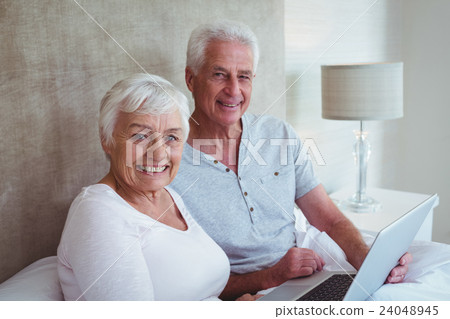 Happy retired couple holding laptop  24048945