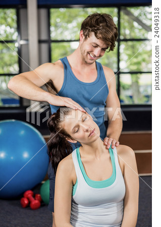 Trainer assisting woman with neck exercise Trainer assisting woman with neck exercise 24049318