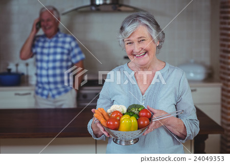 Senior woman holding colander with vegetables Senior woman holding colander with vegetables 24049353