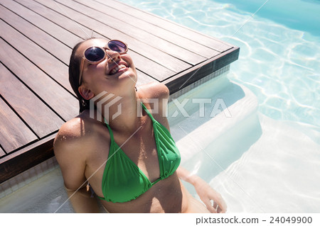 Woman enjoying sunbath in swimming pool 24049900