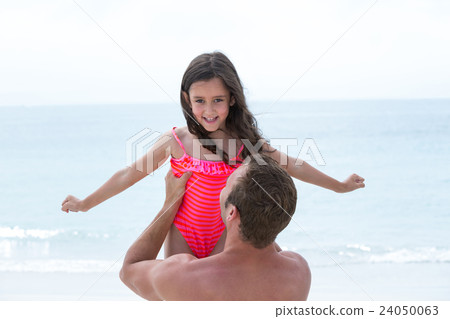 Rear view of father carrying daughter at beach  24050063