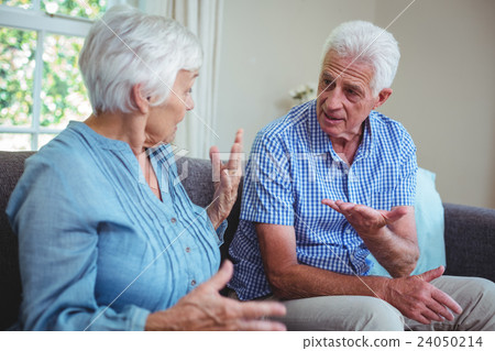 Senior couple arguing while sitting on sofa Senior couple arguing while sitting on sofa 24050214