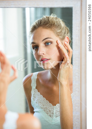 Woman checking her skin in bathroom Woman checking her skin in bathroom 24050366