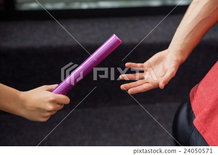 Athlete passing a baton to the partner 24050571