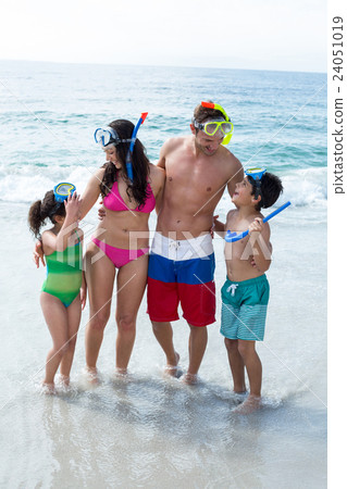 Family wearing diving goggles standing on sea shore 24051019