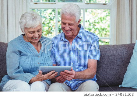 Smiling retired couple using tablet Smiling retired couple using tablet 24051108