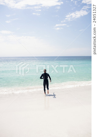 Surfer running towards sea with a surfboard Surfer running towards sea with a surfboard 24051327