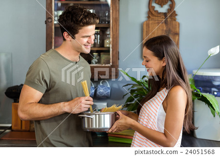 Happy young couple cooking food in kitchen Happy young couple cooking food in kitchen 24051568
