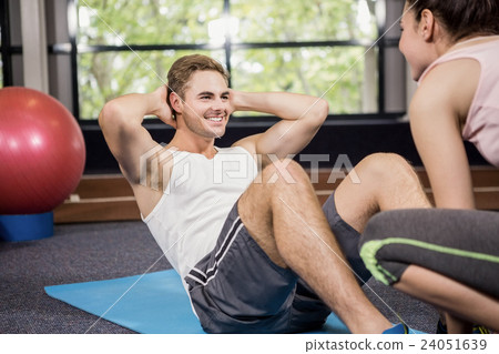 Trainer assisting man with abdominal crunches Trainer assisting man with abdominal crunches 24051639