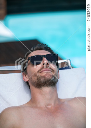 Handsome man in sunglasses relaxing on a sun lounger Handsome man in sunglasses relaxing on a sun lounger 24052059