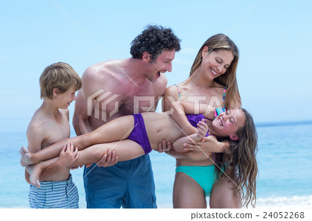 Happy family lifting girl while standing at sea shore 24052268