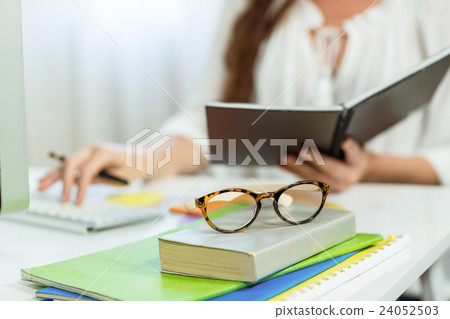 Midsection of businesswoman holding notepad at desk Midsection of businesswoman holding notepad at desk 24052503