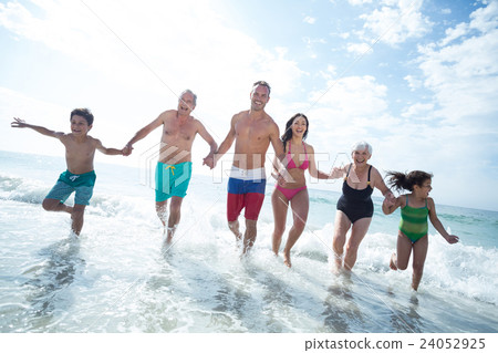 Multi- generation family running at beach  24052925