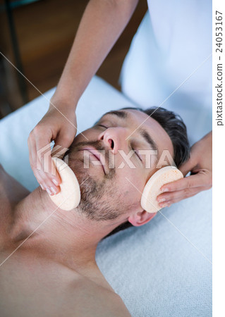 Man receiving a facial massage from masseur Man receiving a facial massage from masseur 24053167