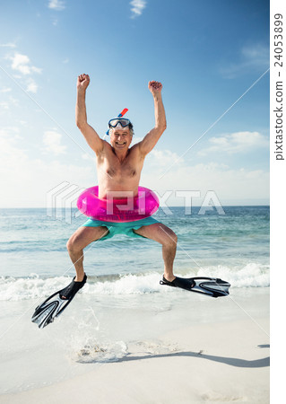 Happy senior man in inflatable ring and flippers jumping on beach Happy senior man in inflatable ring and flippers jumping on beach 24053899