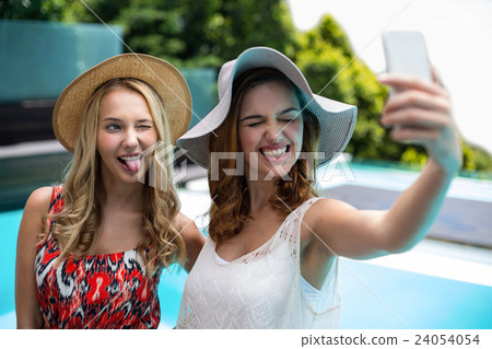Beautiful women taking a selfie by swimming pool 24054054