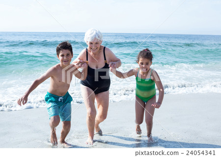 Grandmother with grandchildren running at beach  24054341
