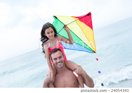 Father carrying daughter with kite at beach Father carrying daughter with kite at beach 24054393