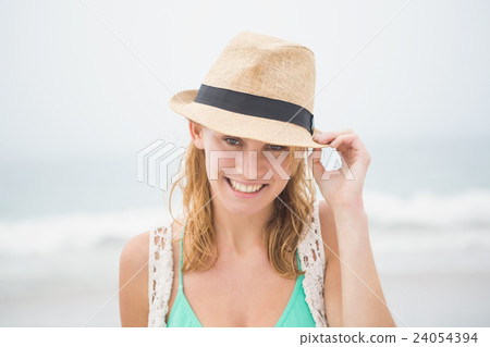 Cute blonde woman holding her straw hat Cute blonde woman holding her straw hat 24054394