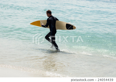 Surfer running on the beach with a surfboard Surfer running on the beach with a surfboard 24054439