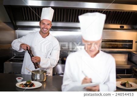 Portrait of smiling male chef preparing food in kitchen Portrait of smiling male chef preparing food in kitchen 24054453