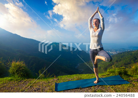 Woman in  yoga asana Vrikshasana tree pose in 24056488