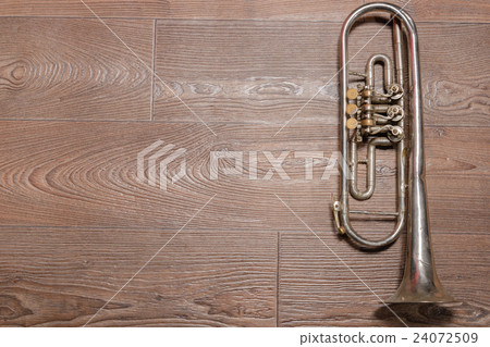 Old rusty trumpet lays on wooden floor Old rusty trumpet lays on wooden floor 24072509