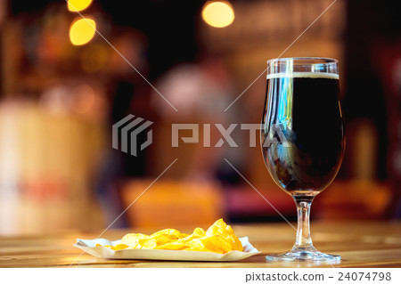 A fresh glass of cold dark beer and potato chips A fresh glass of cold dark beer and potato chips 24074798