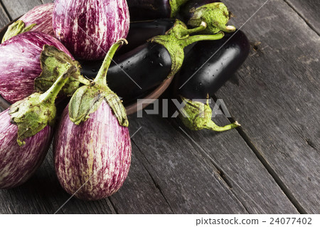 Various eggplants on a dark wooden background 24077402