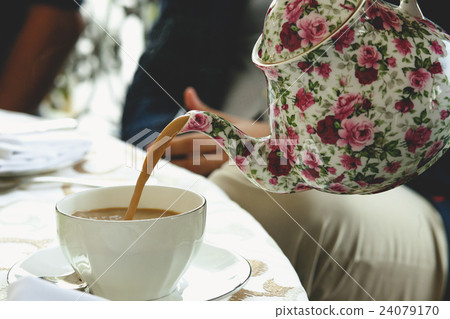 Tea pours from the pot painted with pink flowers 24079170