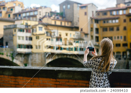 Girl takes a picture of an old city on her phone Girl takes a picture of an old city on her phone 24099410