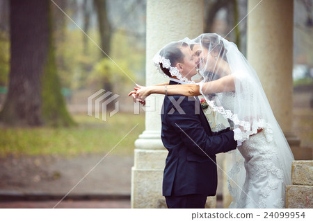 Groom kisses a bride standing hidden  24099954