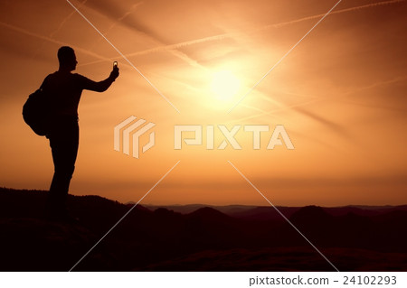 Tall backpacker with phone in hand. Spring daybreak 24102293