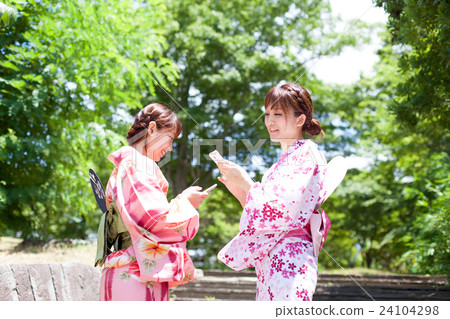 A woman in a yukata manipulating a smartphone A woman in a yukata manipulating a smartphone 24104298