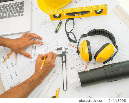 Hand over Construction plans with yellow helmet and drawing tools on blueprints . Hand over Construction plans with yellow helmet and drawing tools on blueprints . 24118098