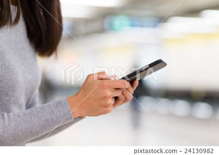 Woman use of mobile phone at train station 24130982