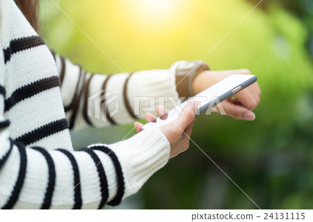 Woman connecting cellphone and smartwatch Woman connecting cellphone and smartwatch 24131115