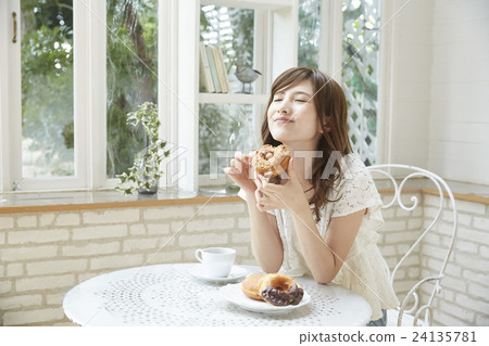 A young lady who eats deliciously a donut 24135781