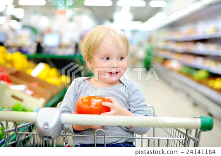 Toddler sitting in the shopping cart in a supermarket Toddler sitting in the shopping cart in a supermarket 24141184