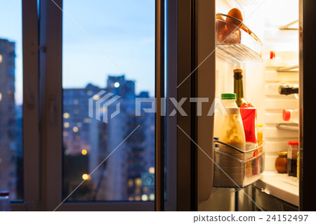Open door of refrigerator with meal in evening 24152497