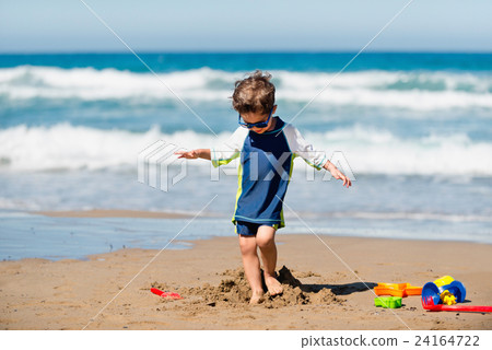 Little boy demolishing sand castle 24164722