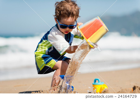 Little boy pouring water from bucket 24164729