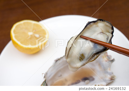 牡蠣抓住煮熟的牡蠣放在白盤子裡用筷子 24169132