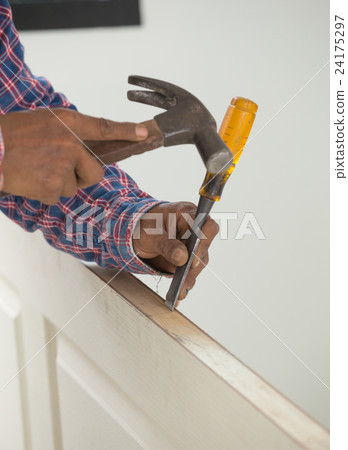 carpenter installer with hammer and chisel at door 24175297