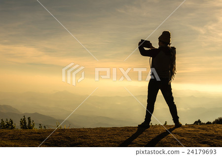 silhouette of a man with action take photo by tablet over the mountains landscape silhouette of a man with action take photo by tablet over the mountains landscape 24179693