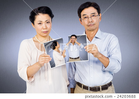 Composite image of asian couple holding a photo Composite image of asian couple holding a photo 24203688