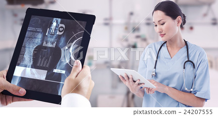 Composite image of surgeon using digital tablet with group around table in hospital Composite image of surgeon using digital tablet with group around table in hospital 24207555