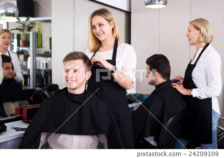 Positive blonde hairdresser serving teenager 24209109