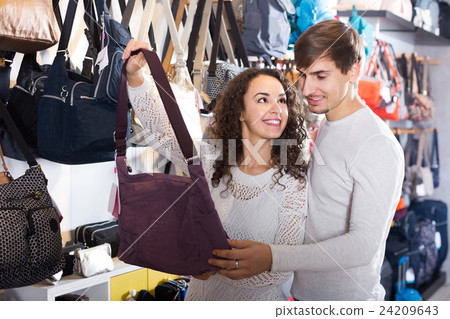 customers looking at stylish female handbags in store 24209643