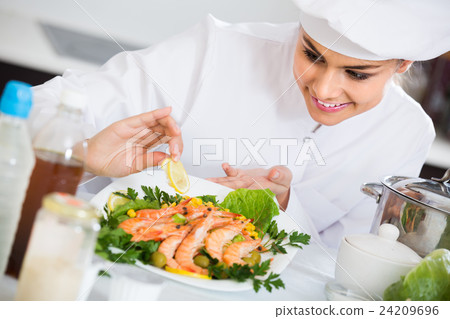 Professional female cook decorating prepared dish of shrimps Professional female cook decorating prepared dish of shrimps 24209696
